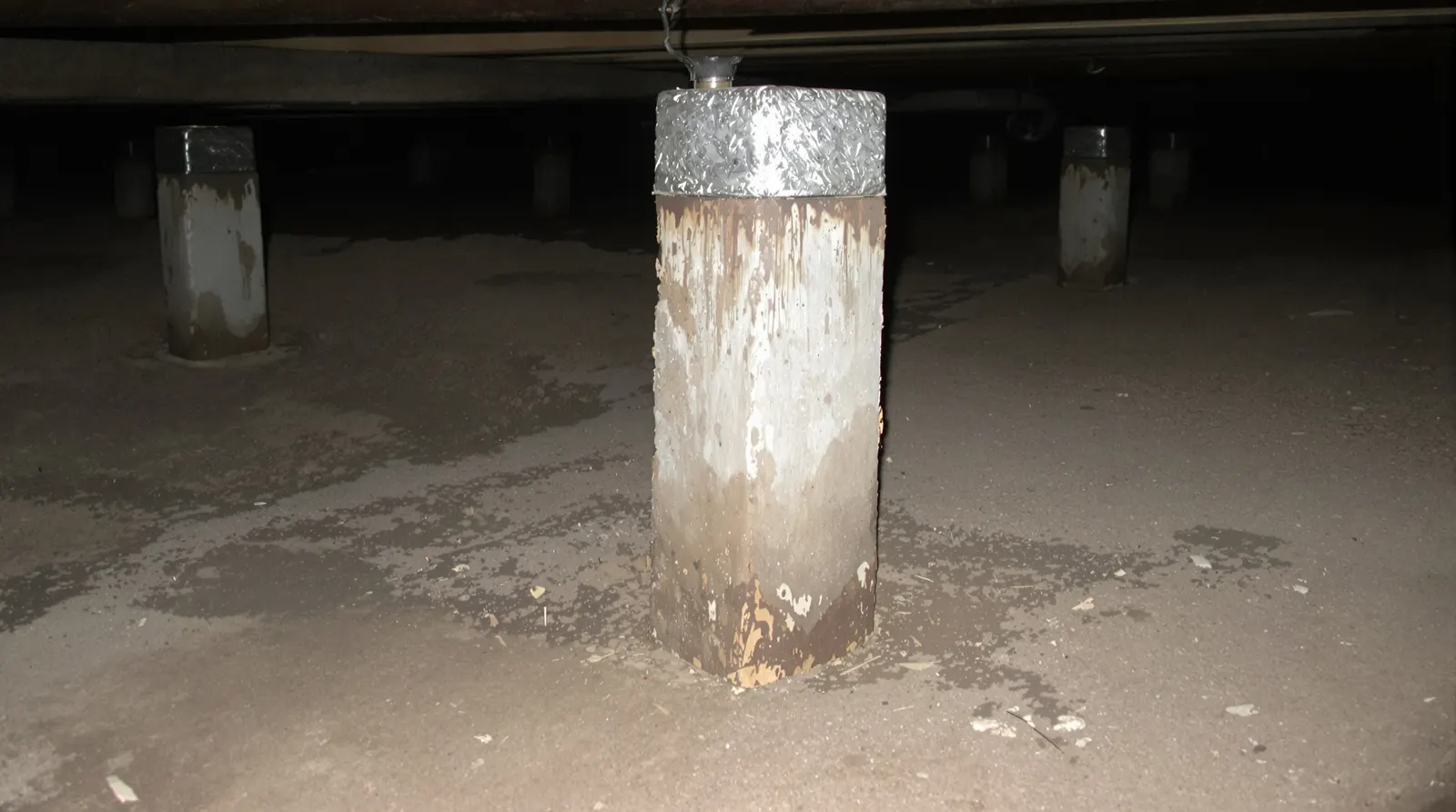 Old timber house stump with rot at the base in a dim subfloor